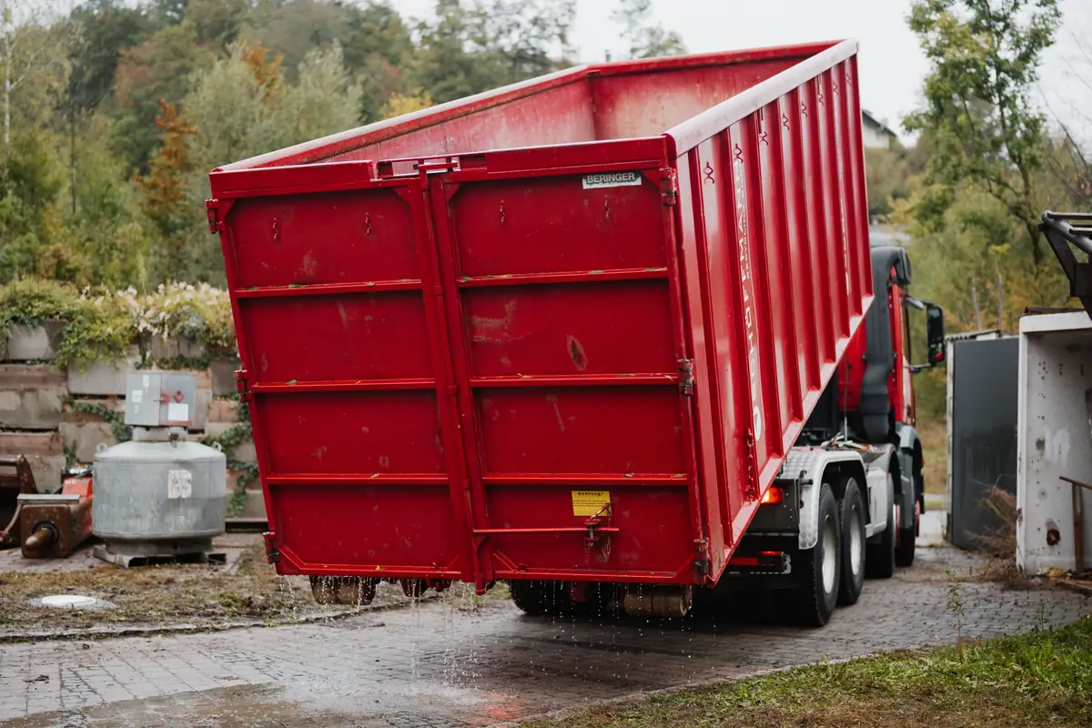 Roter Abrollcontainer auf einer Baustelle vor einem Gebaeude